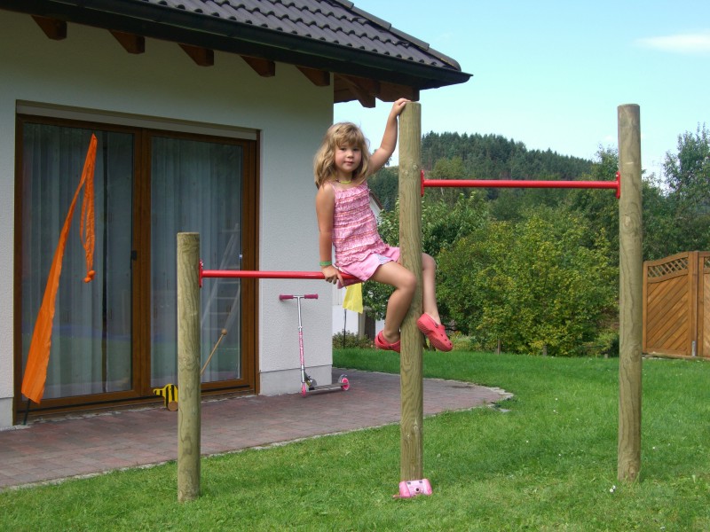 Reck Ein Kind sitzt auf einer Reckstange auf einem Spielgerät Reck